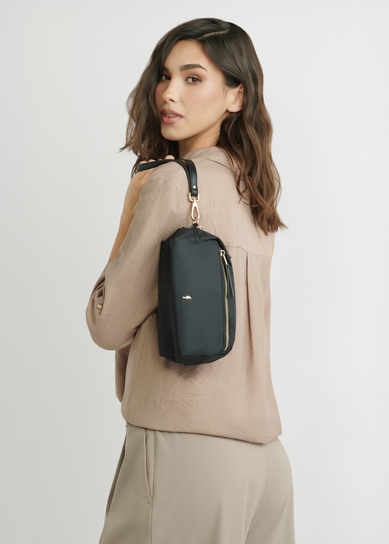 Чорна жіноча косметичка TOREN-0347-99(W26), вигляд виробу на силуеті моделі, на світлому фоні.