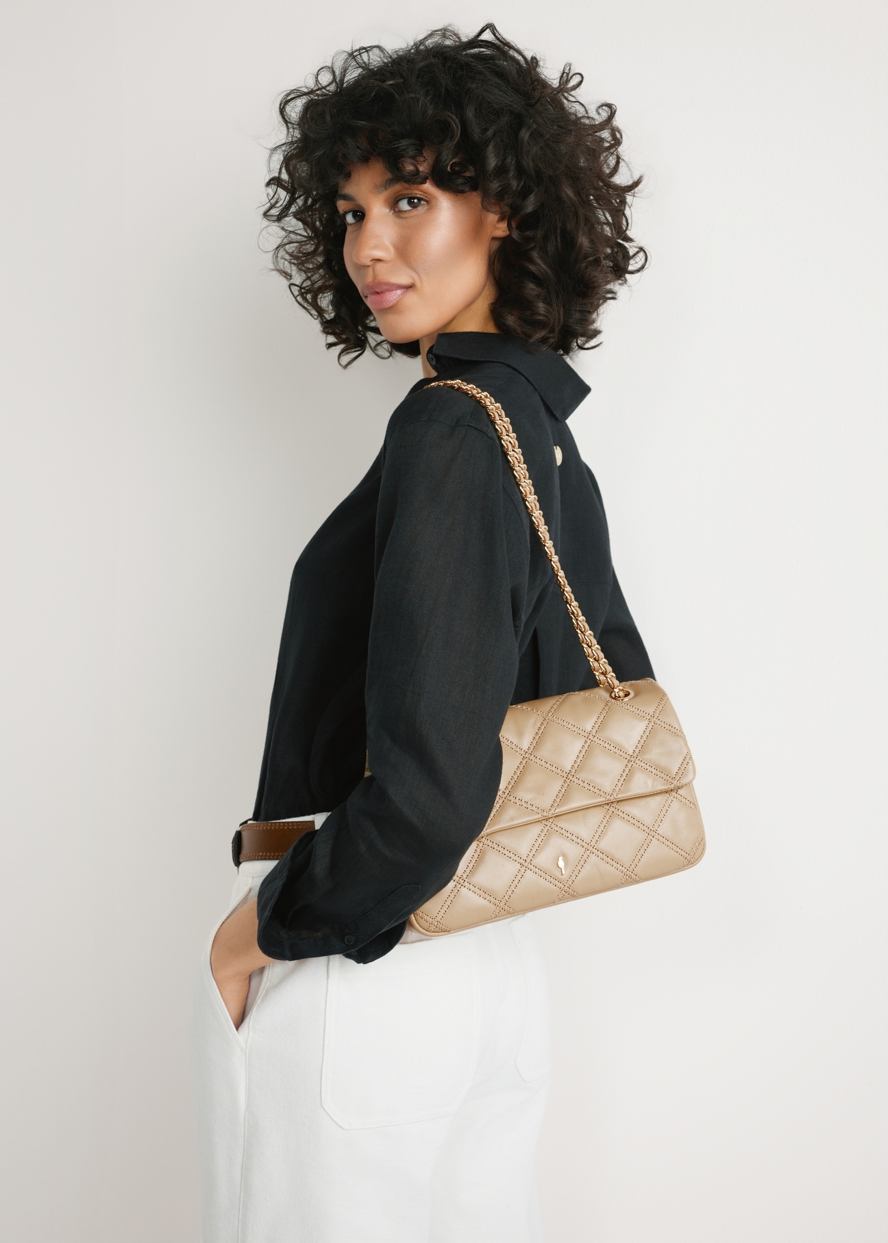 Бежева шкіряна жіноча сумка з ланцюжком TORES-1110-1B(W26) - вигляд виробу спереду, на моделі, на світлому фоні. Видно силует до пояса.