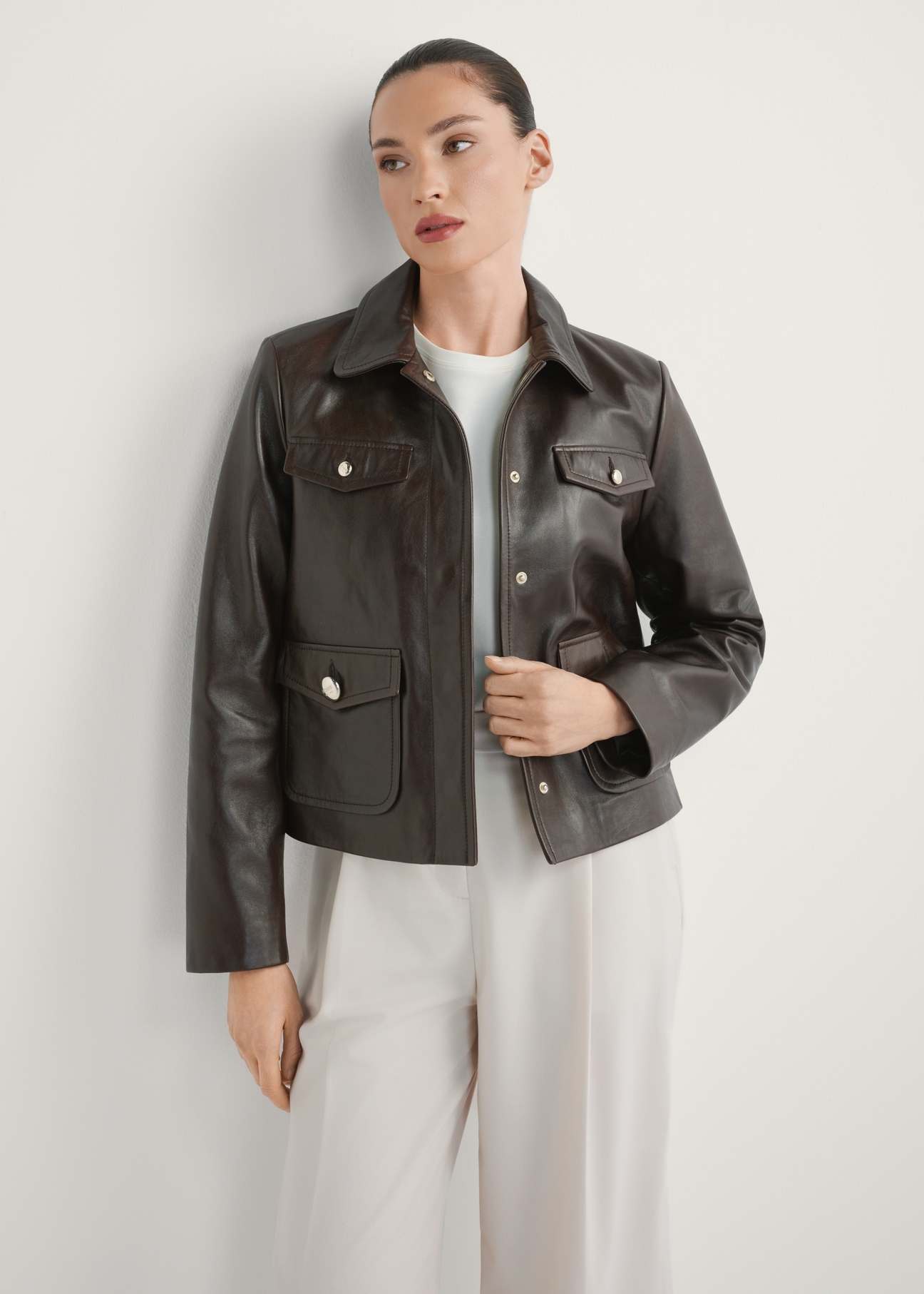 Темно-коричнева жіноча шкіряна куртка KURDS-0589-1I(W26), вигляд виробу спереду на моделі. Видно половину силуету.