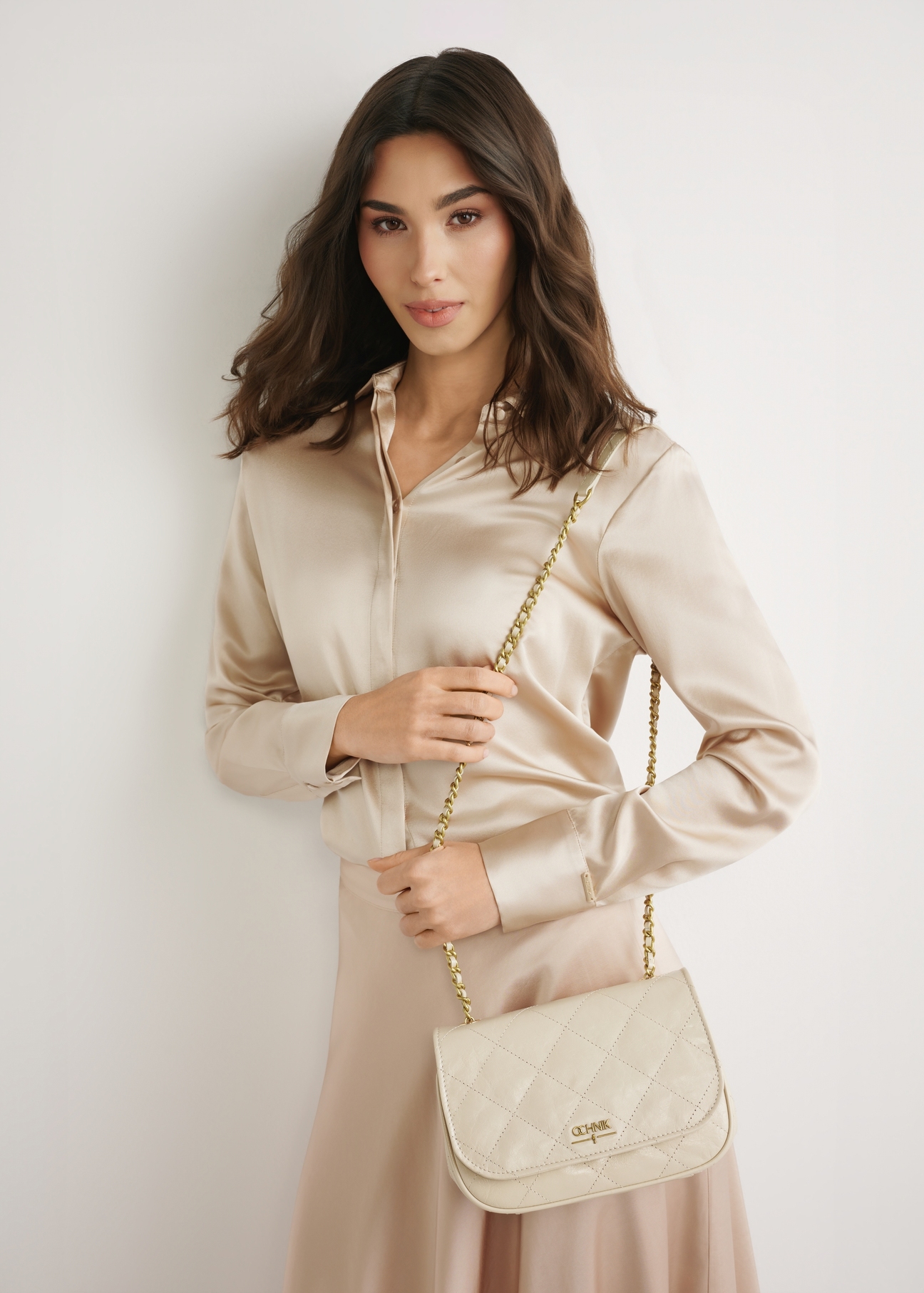 Жіноча сумка кремової лакованої шкіри TORES-1297-0B(W26), вигляд виробу спереду на моделі. Видно силует до коліна.