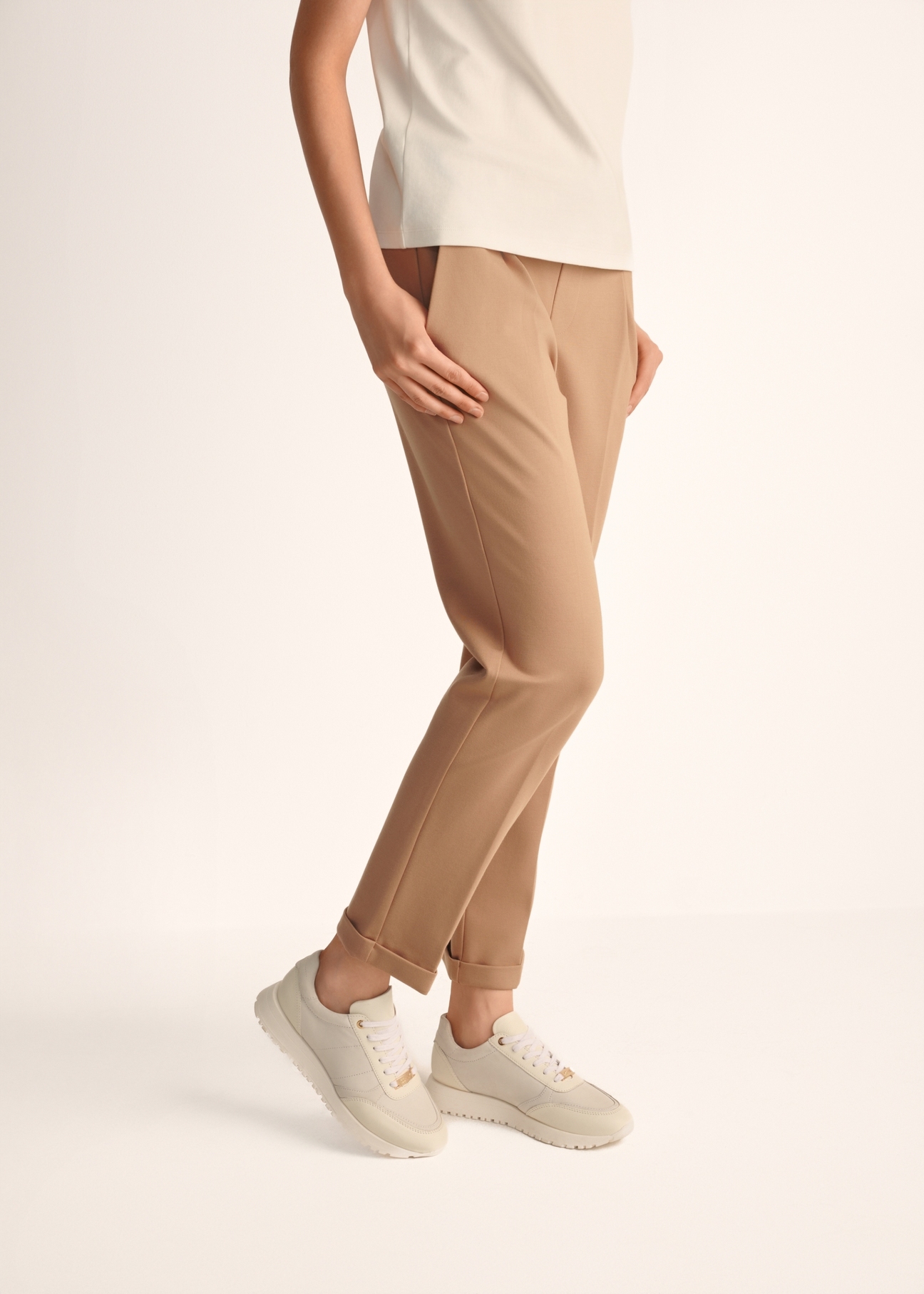 Жіноче спортивне взуття кремового кольору з шкіри BUTYD-1099-11(Z25), вигляд виробу на ногах моделі на світлому фоні.