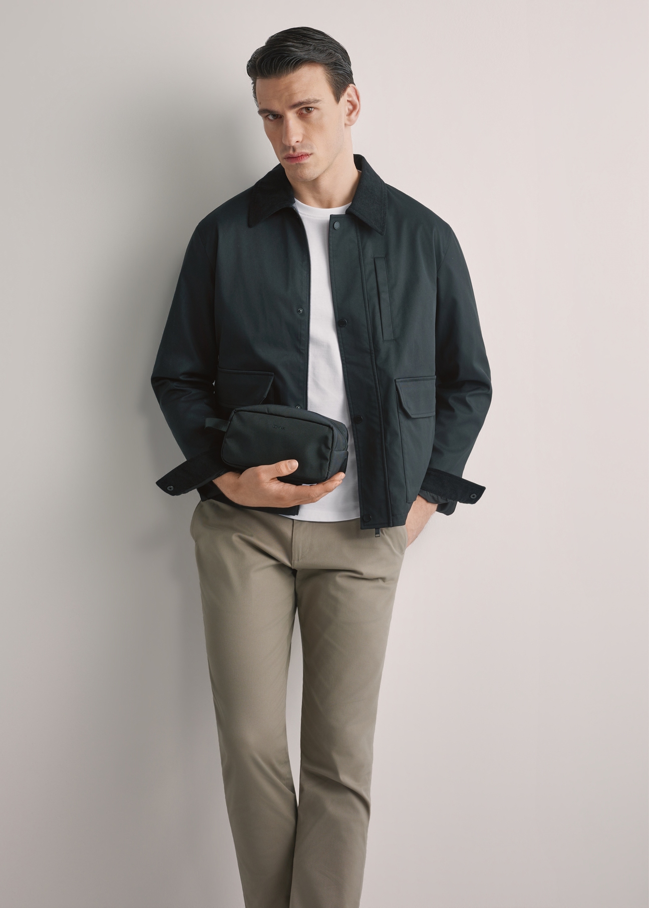 Чорна чоловіча косметичка TORMN-0352-99(W26), вигляд виробу спереду в руці моделі. Видно половину силуету.