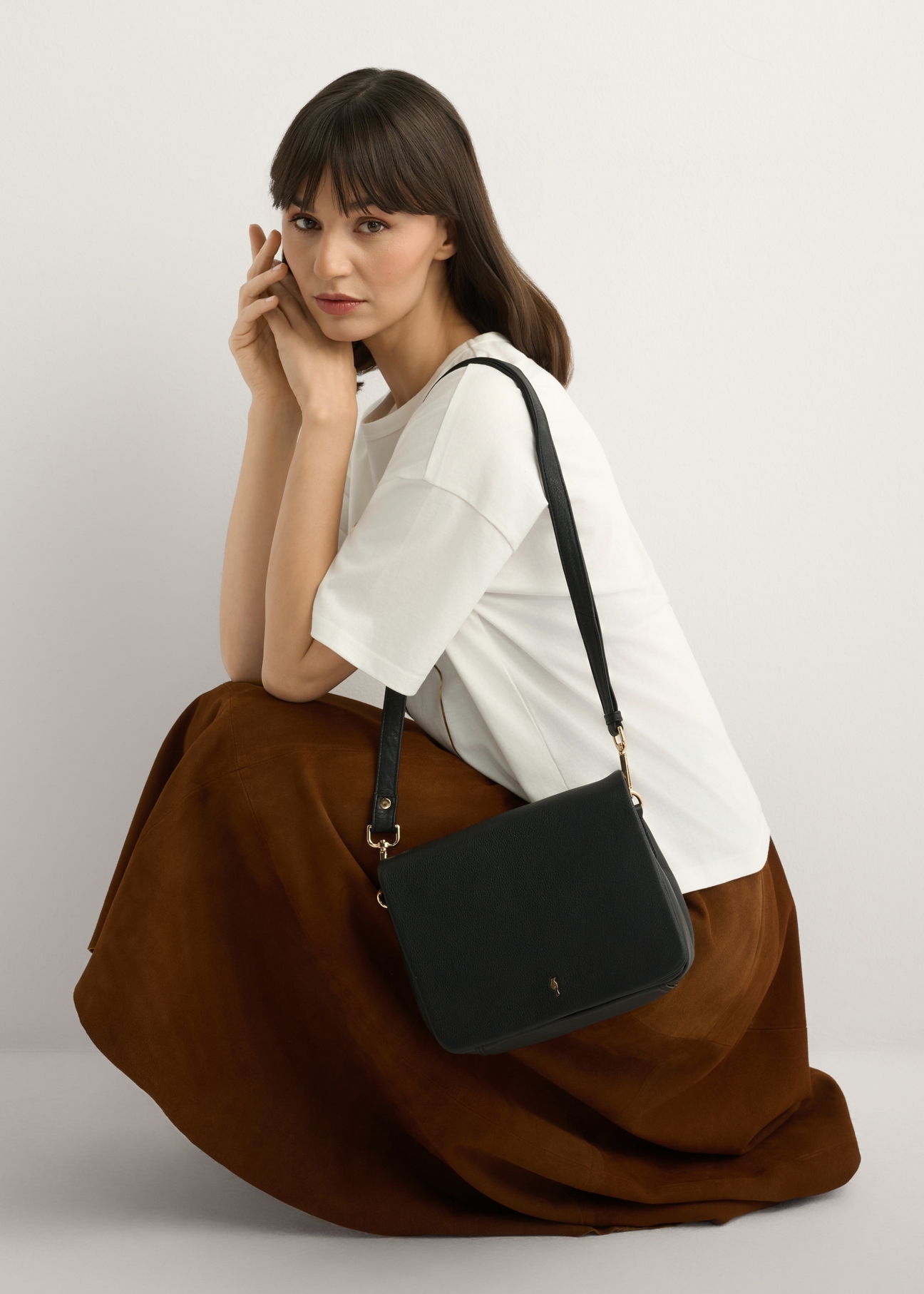 Чорна шкіряна жіноча сумка TORES-0911E-99(Z25), вигляд виробу на плечі моделі, на світлому фоні.