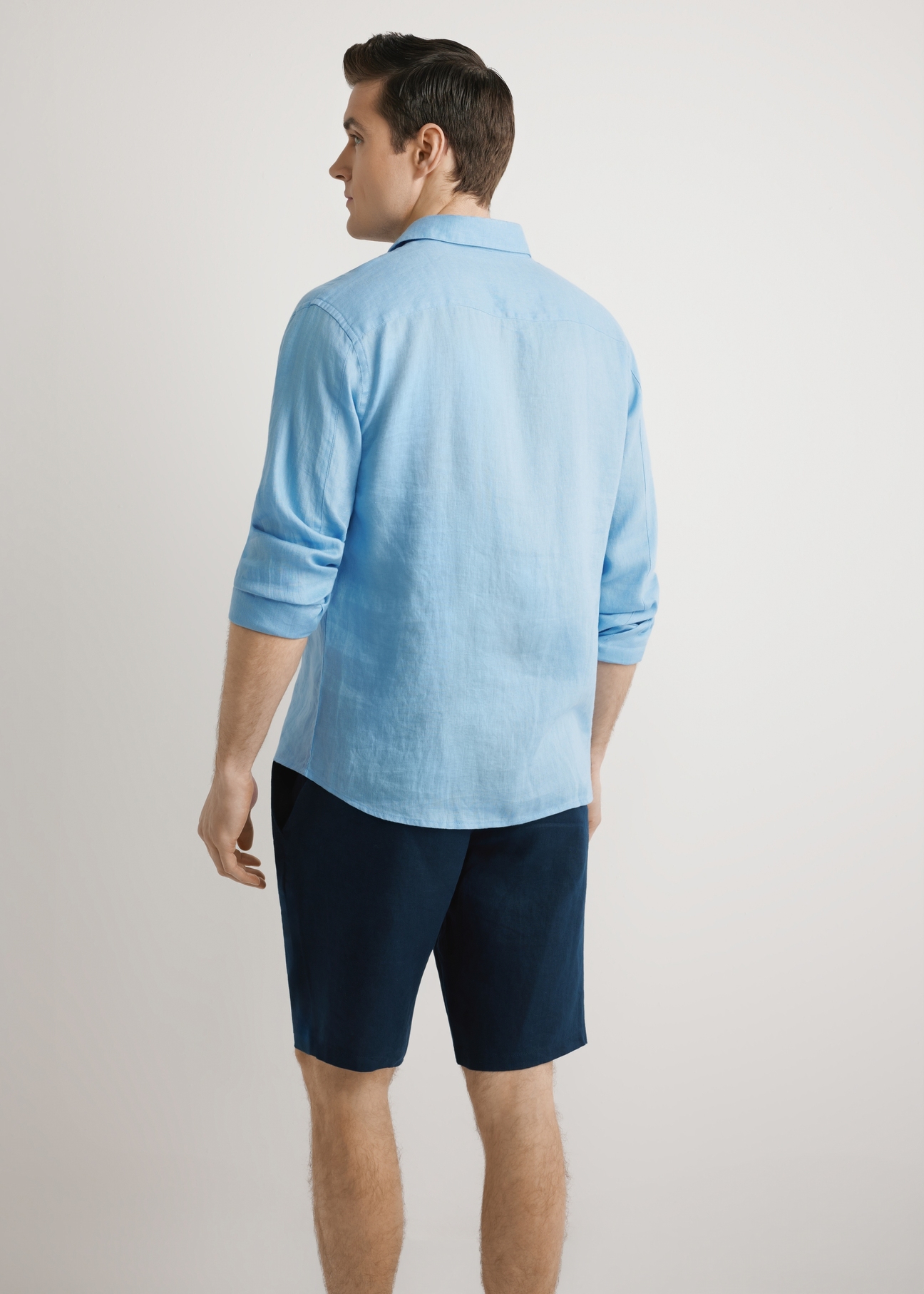 Синя чоловіча лляна сорочка KOSMT-0321A-7B(W26), вигляд виробу ззаду, на моделі, на світлому фоні. Видно половину силуету.