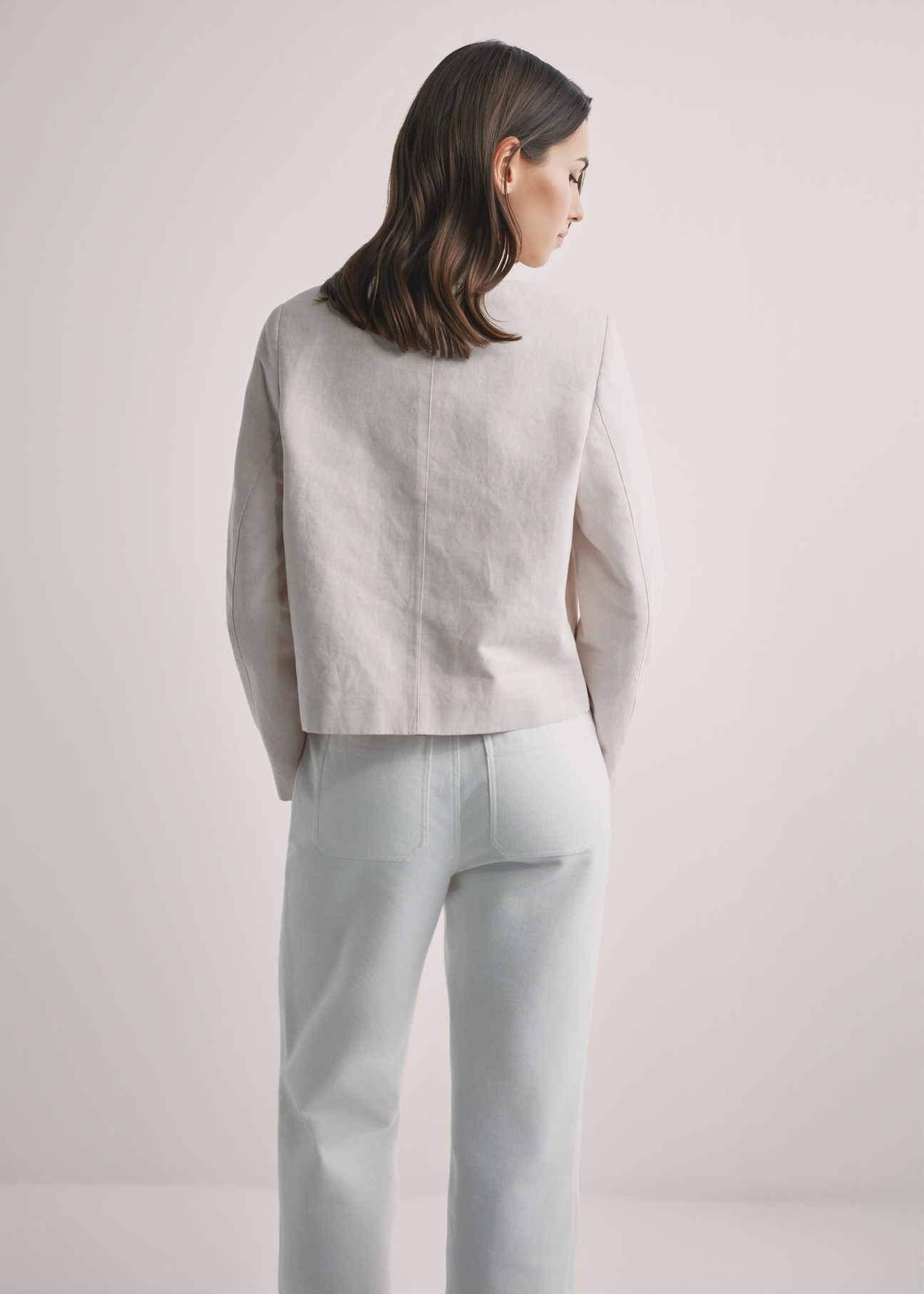 Світло-бежева жіноча лляна куртка KURDT-0652-1A(W26), вигляд виробу ззаду на моделі. Видно половину силуету.