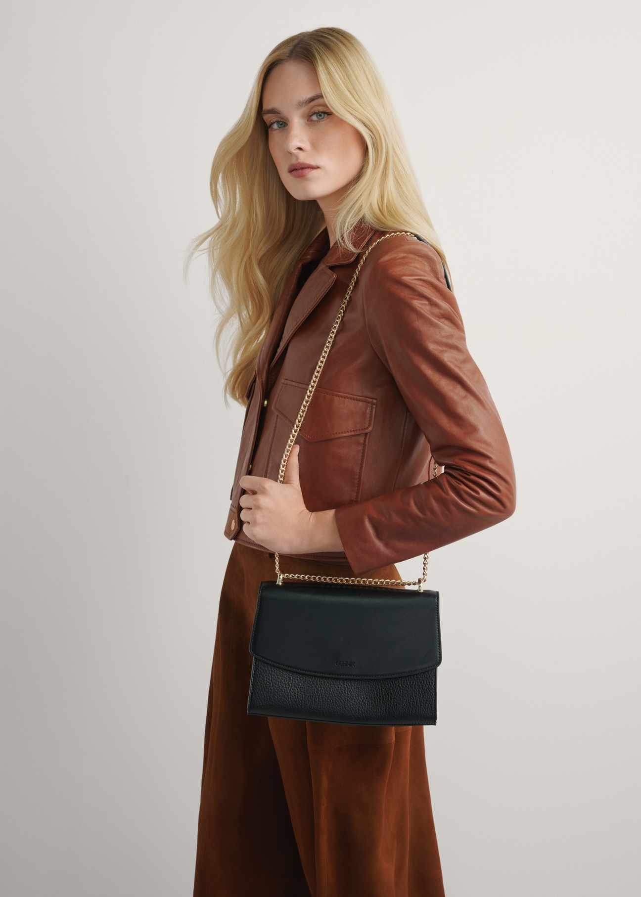 Елегантна чорна жіноча сумка-месенджер TOREC-1165-99(W26), вигляд виробу на плечі моделі. Видно половину силуету.