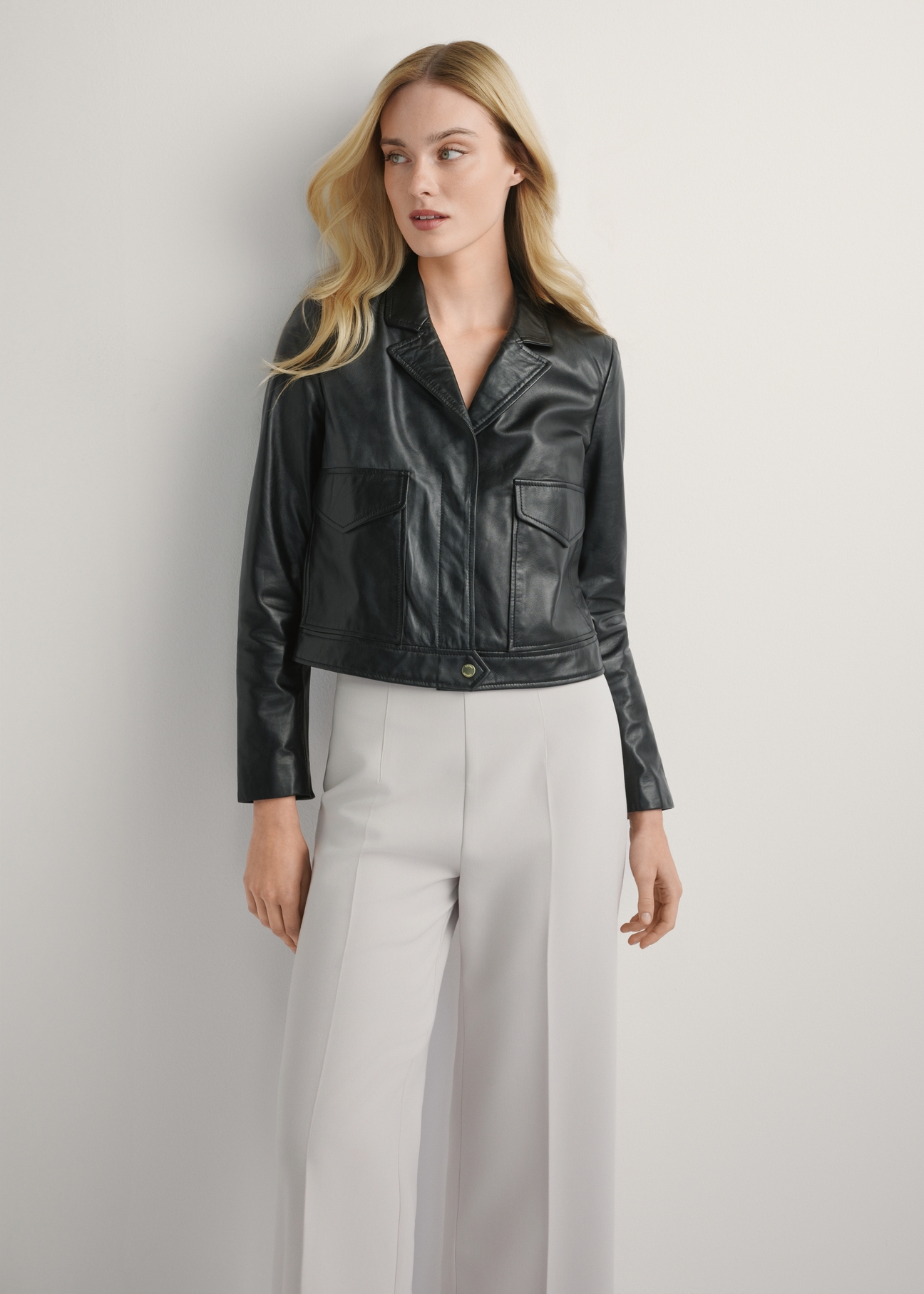 Жіноча чорна шкіряна коротка куртка KURDS-0471-99(W26), вигляд виробу спереду на моделі. Видно половину силуету.