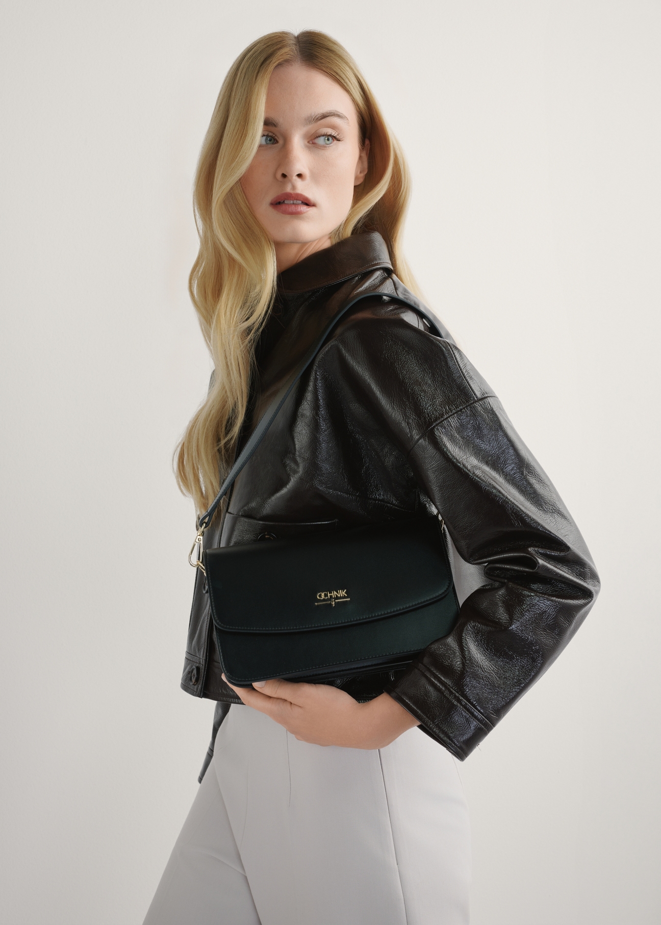 Чорна жіноча сумка зі штучної шкіри TOREC-1081-99(W26), вигляд виробу в руках моделі. Видно половину силуету.