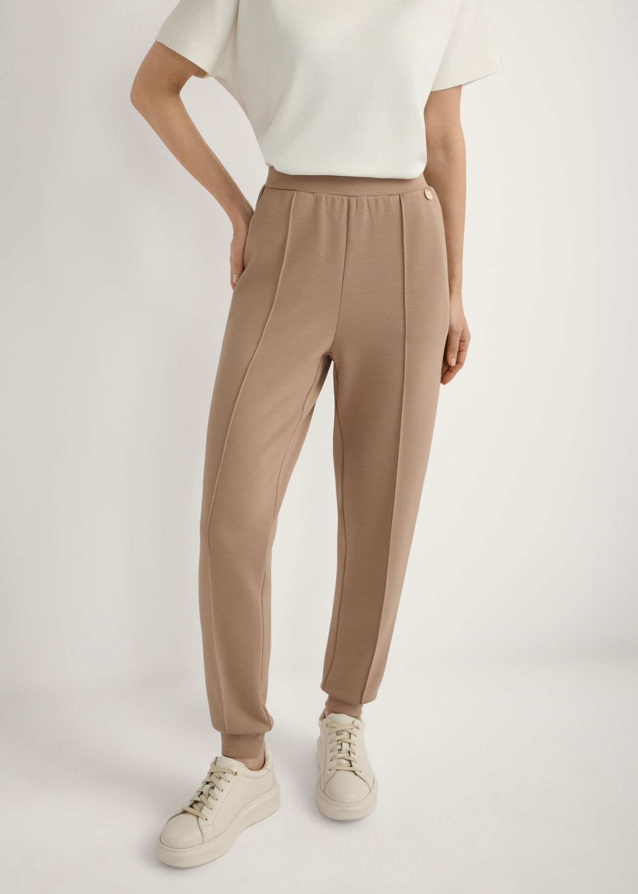 Карамельні завужені штани SPODT-0104 A-1D(W26), вигляд виробу спереду на моделі. Видно половину силуету.