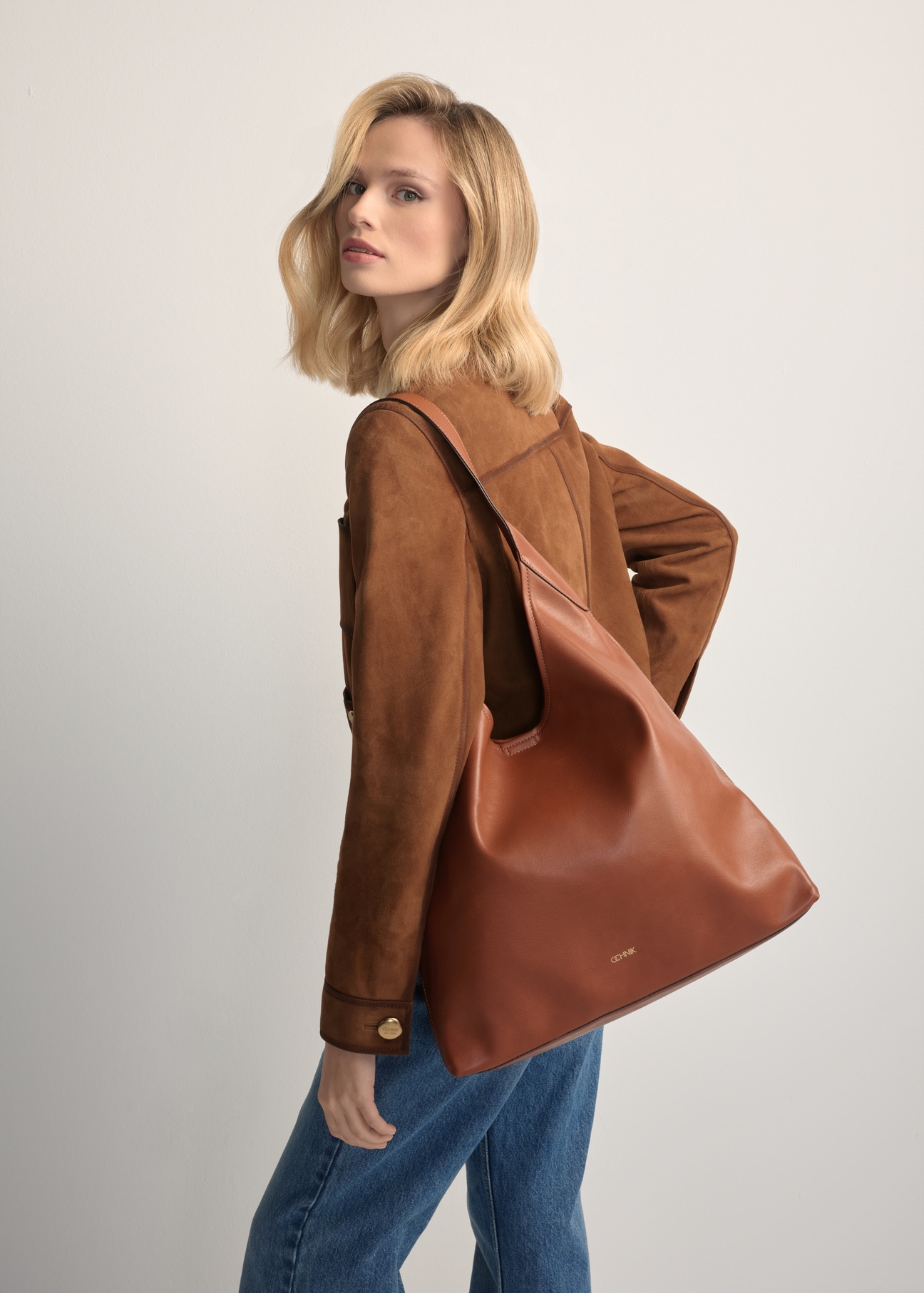 Велика жіноча сумка коньячного кольору TOREC-1199-1F(W26), вигляд виробу на плечі моделі. Видно половину силуету.