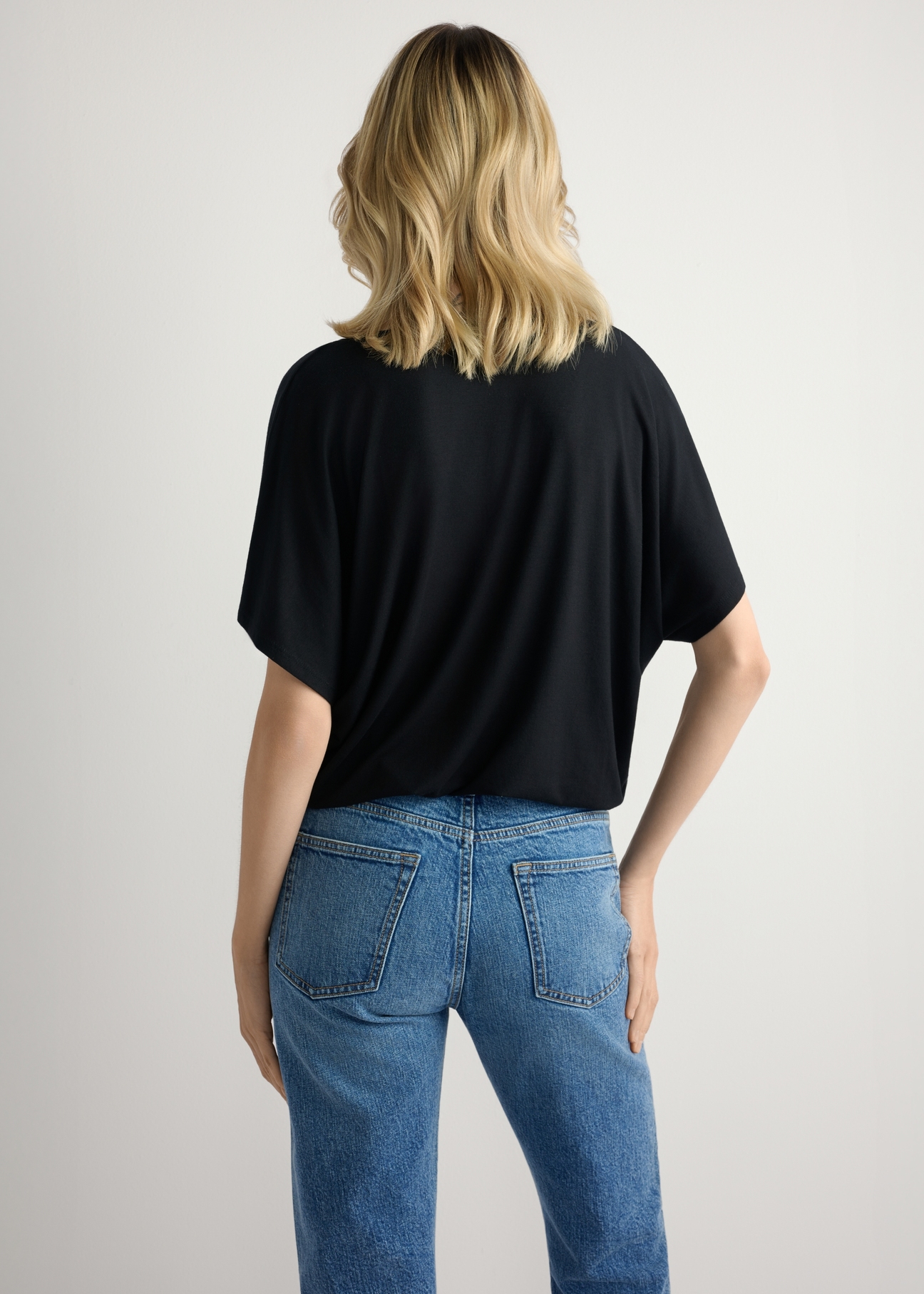 Чорна жіноча блузка BLUDT-0202-99(W26), вигляд виробу ззаду на моделі. Видно половину силуету.