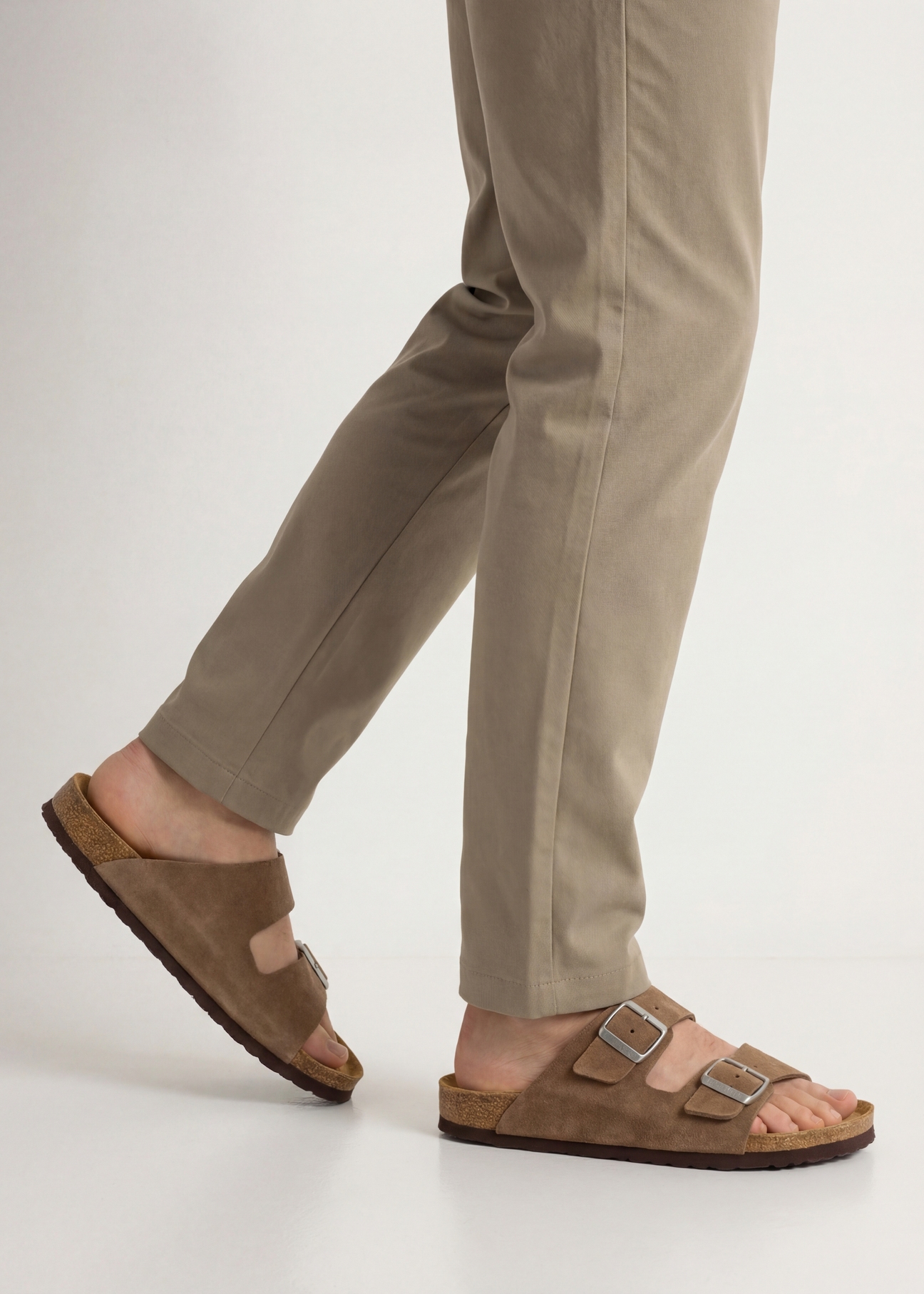 Чоловічі шкіряні шльопанці холодного бежевого кольору BUTYM-0495-1K(W26), вигляд виробу збоку на ногах моделі.