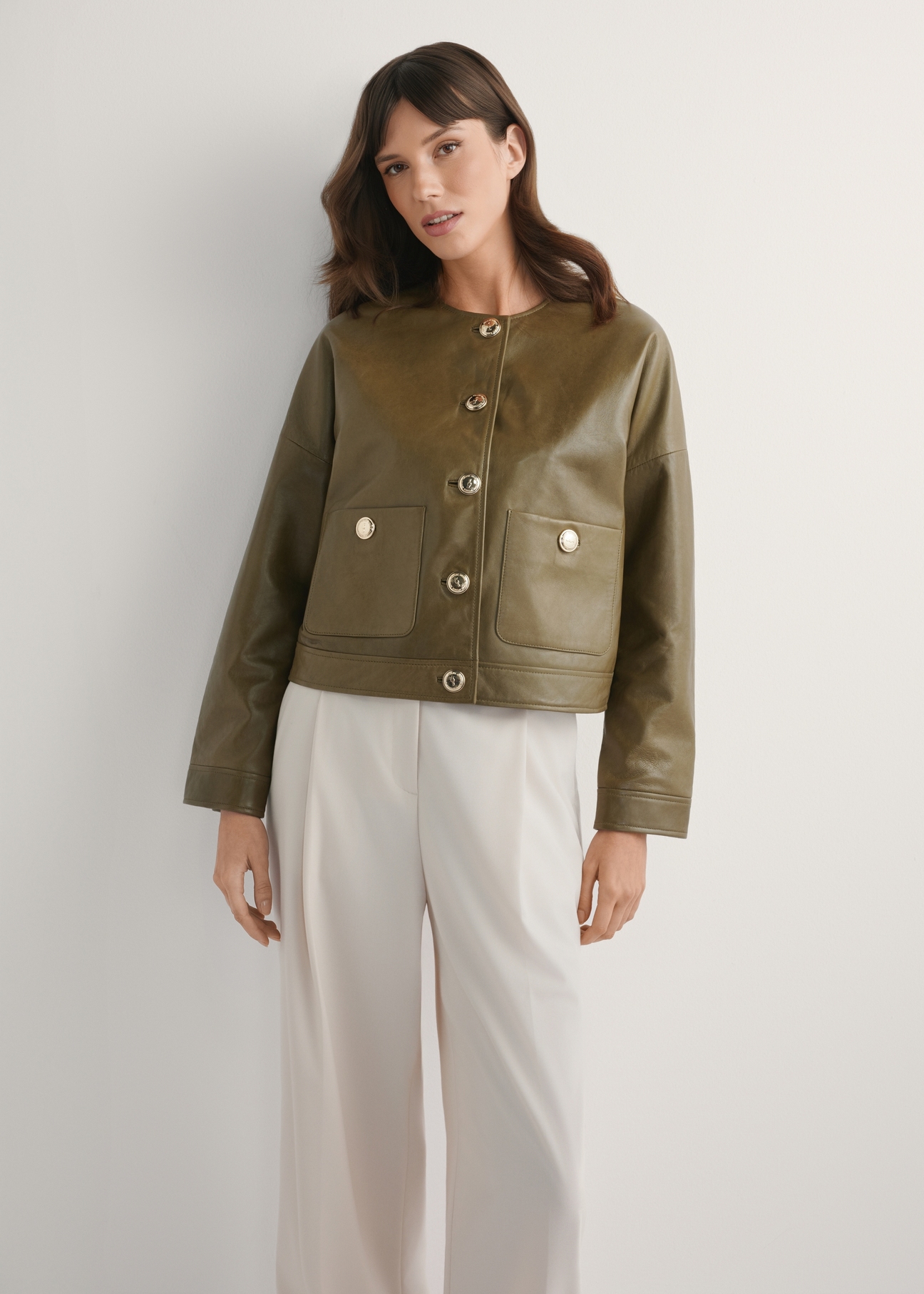 Жіноча коротка шкіряна куртка кольору хакі KURDS-0590-8D(W26), вигляд виробу спереду на моделі. Видно половину силуету.