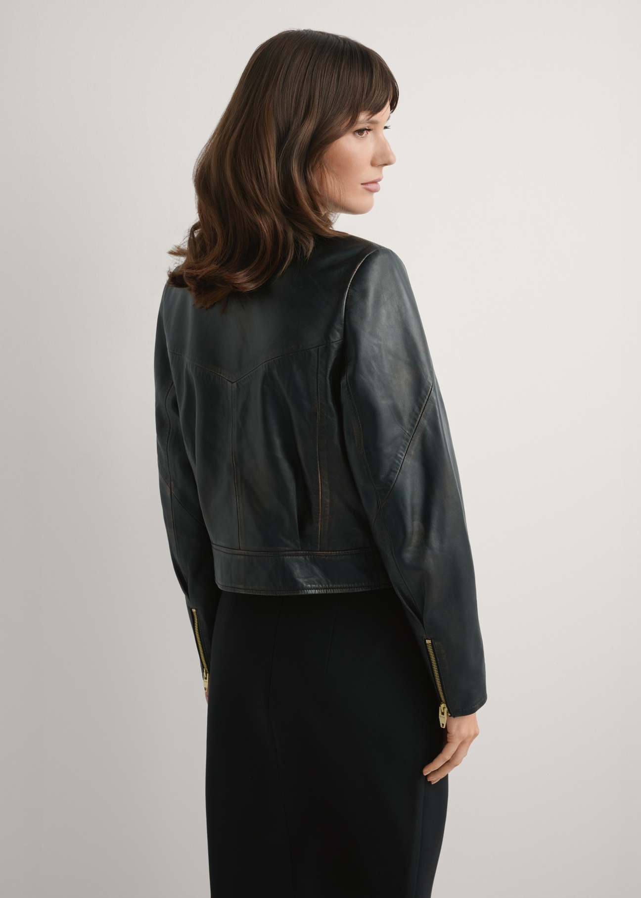 Жіноча вінтажна коротка шкіряна куртка KURDS-0573-9J(W26), вигляд виробу зі спини на моделі. Видно половину силуету.