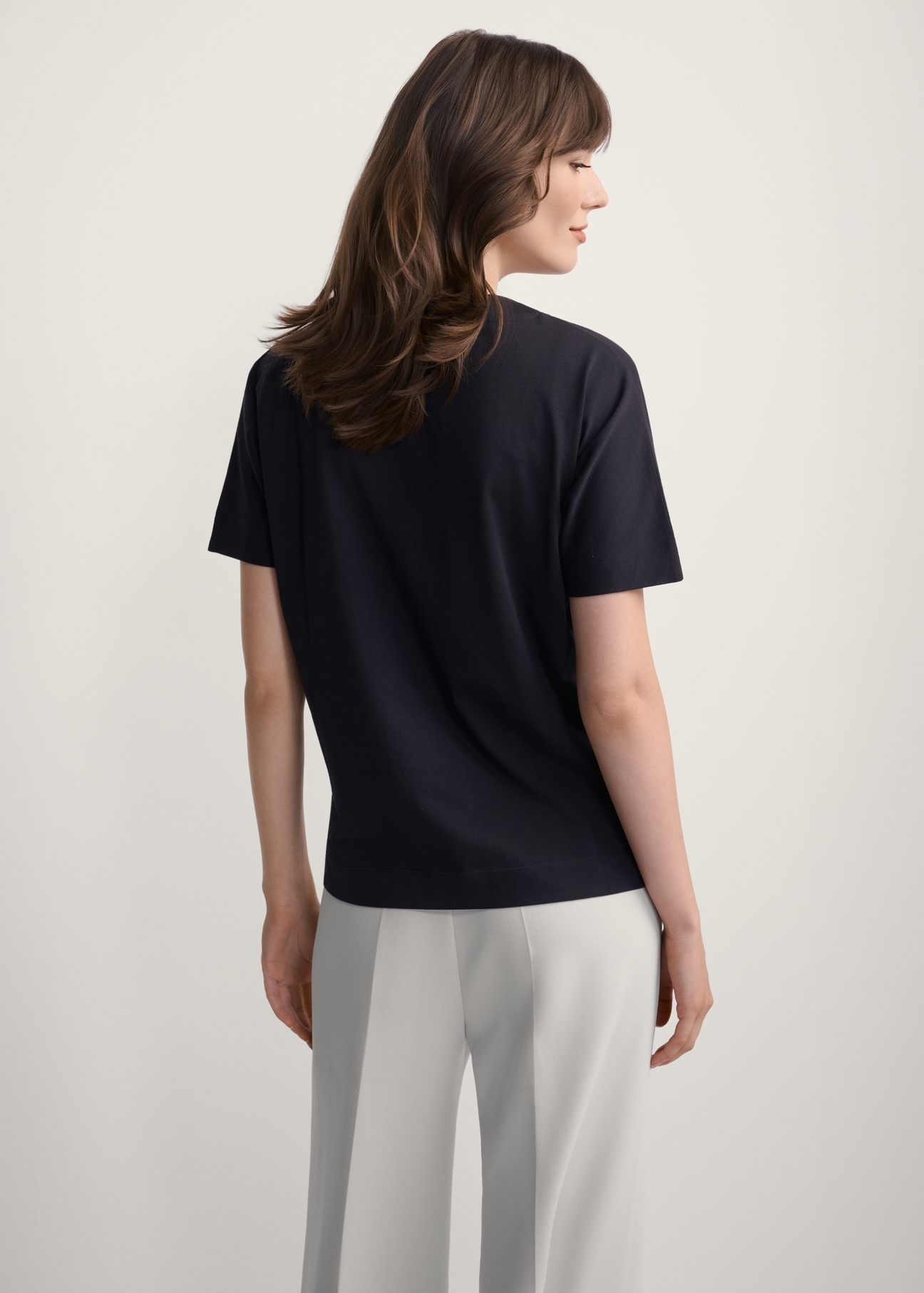 Жіноча чорна футболка з принтом TSHDT-0146-99(Z25), вигляд виробу ззаду на моделі. Видно половину силуету.