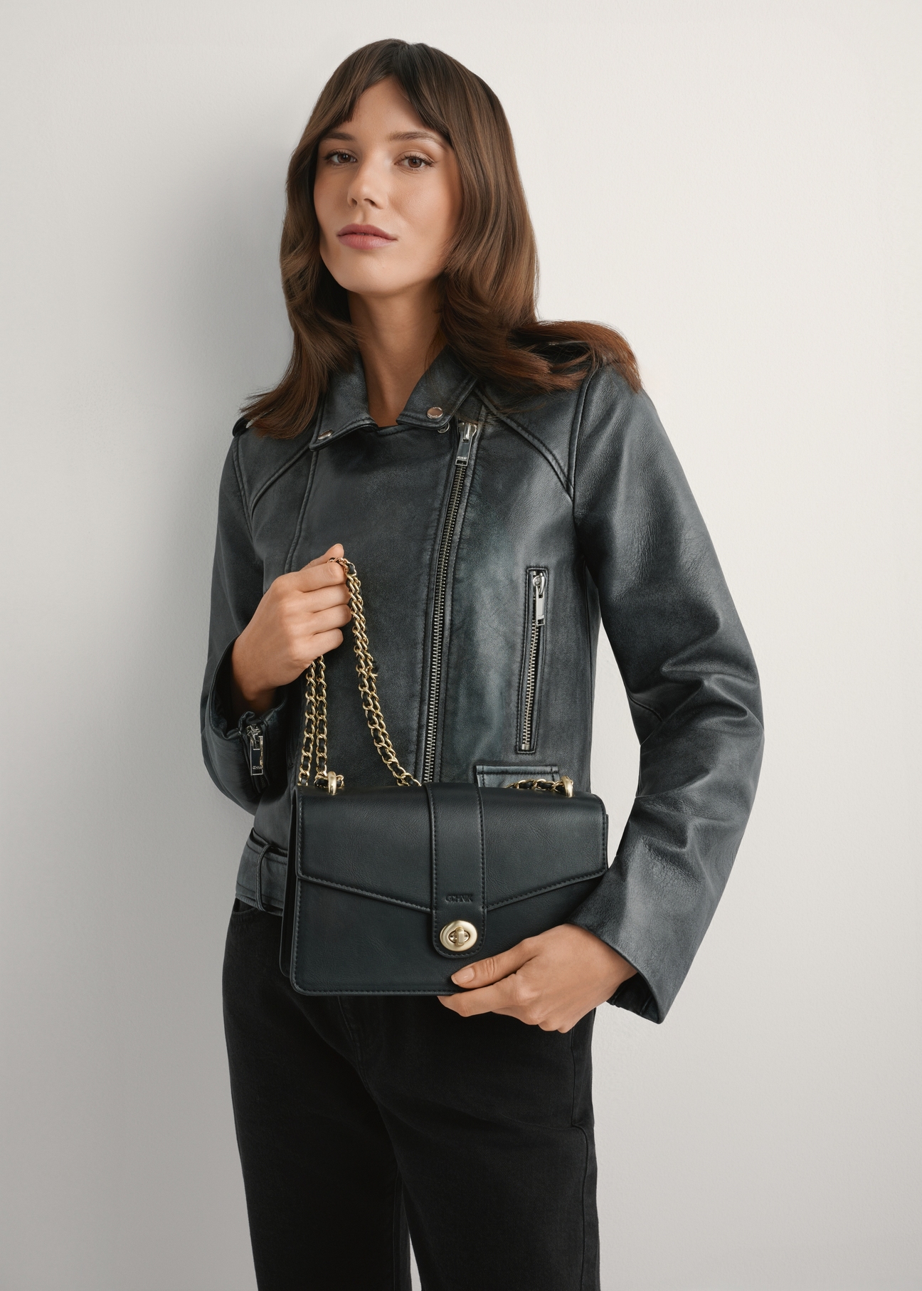 Чорна жіноча сумка-месенджер TOREC-1137-99(W26), вигляд виробу в руках моделі. Видно половину силуету.