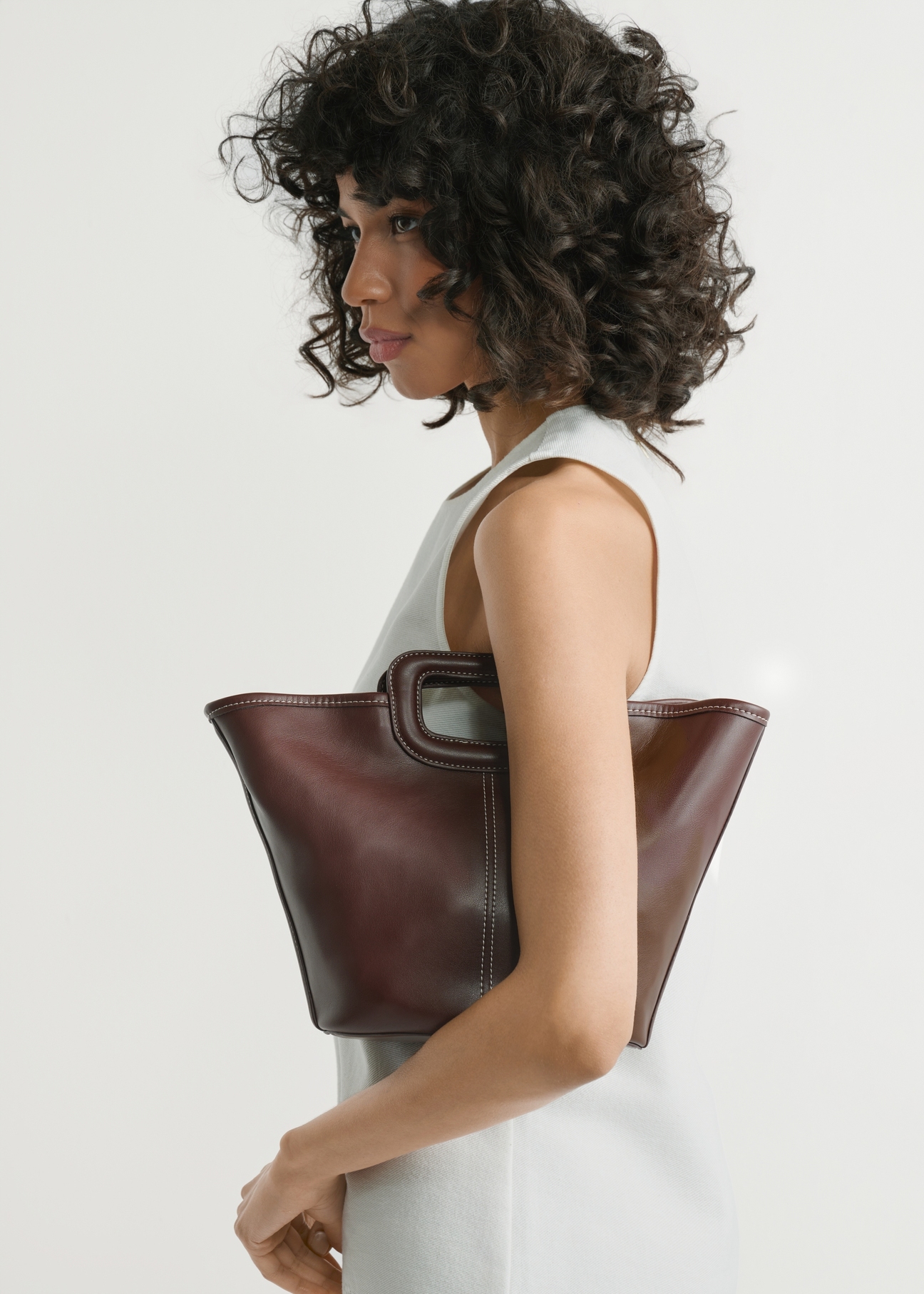 Темно-коричнева жіноча сумка з прострочкою TOREC-1213-1H(W26), вигляд виробу в руках моделі. Видно половину силуету.
