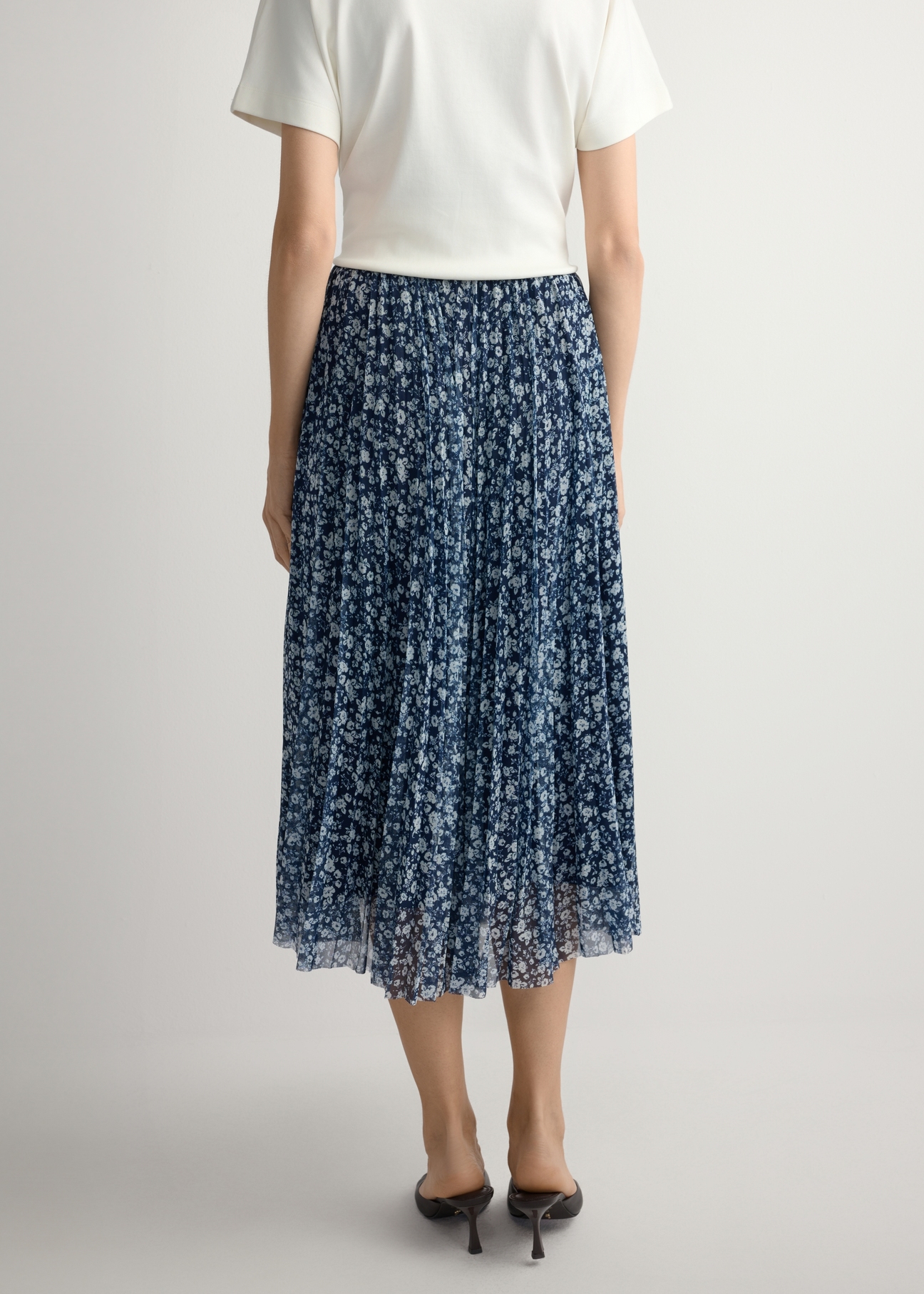 Квіткова плісована спідниця міді SPCDT-0110-7P(W26), вигляд виробу ззаду на моделі. Видно половину силуету.