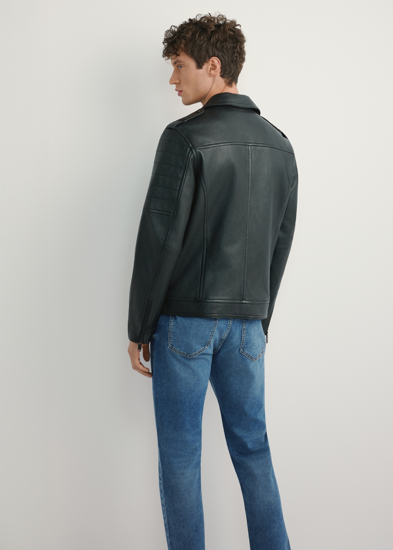 Чоловіча чорна шкіряна байкерська куртка KURMS-0391-99(W26), вигляд виробу зі спини на моделі. Видно половину силуету.