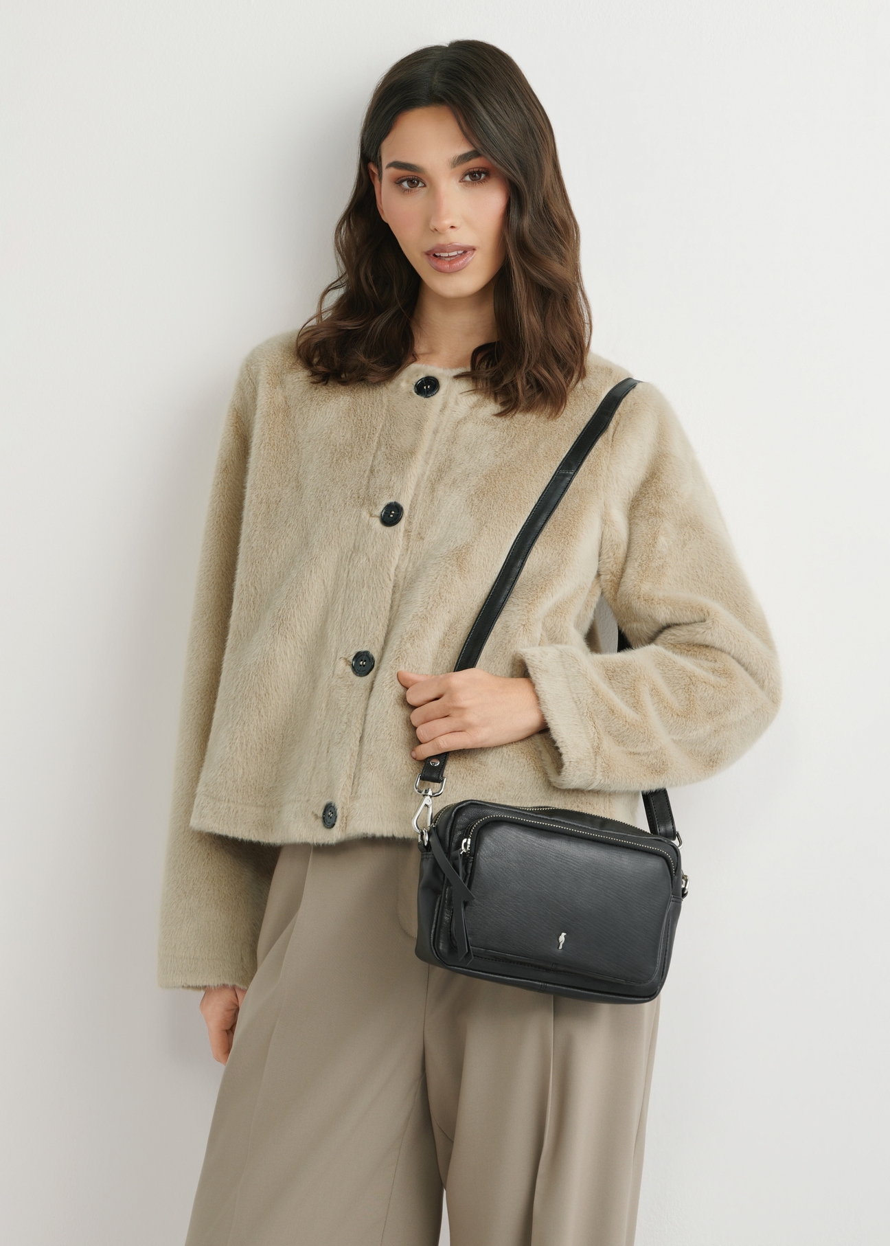 Маленька чорна шкіряна жіноча сумочка TORES-1023A-99(W26), вигляд виробу спереду на плечі моделі. Видно половину силуету.