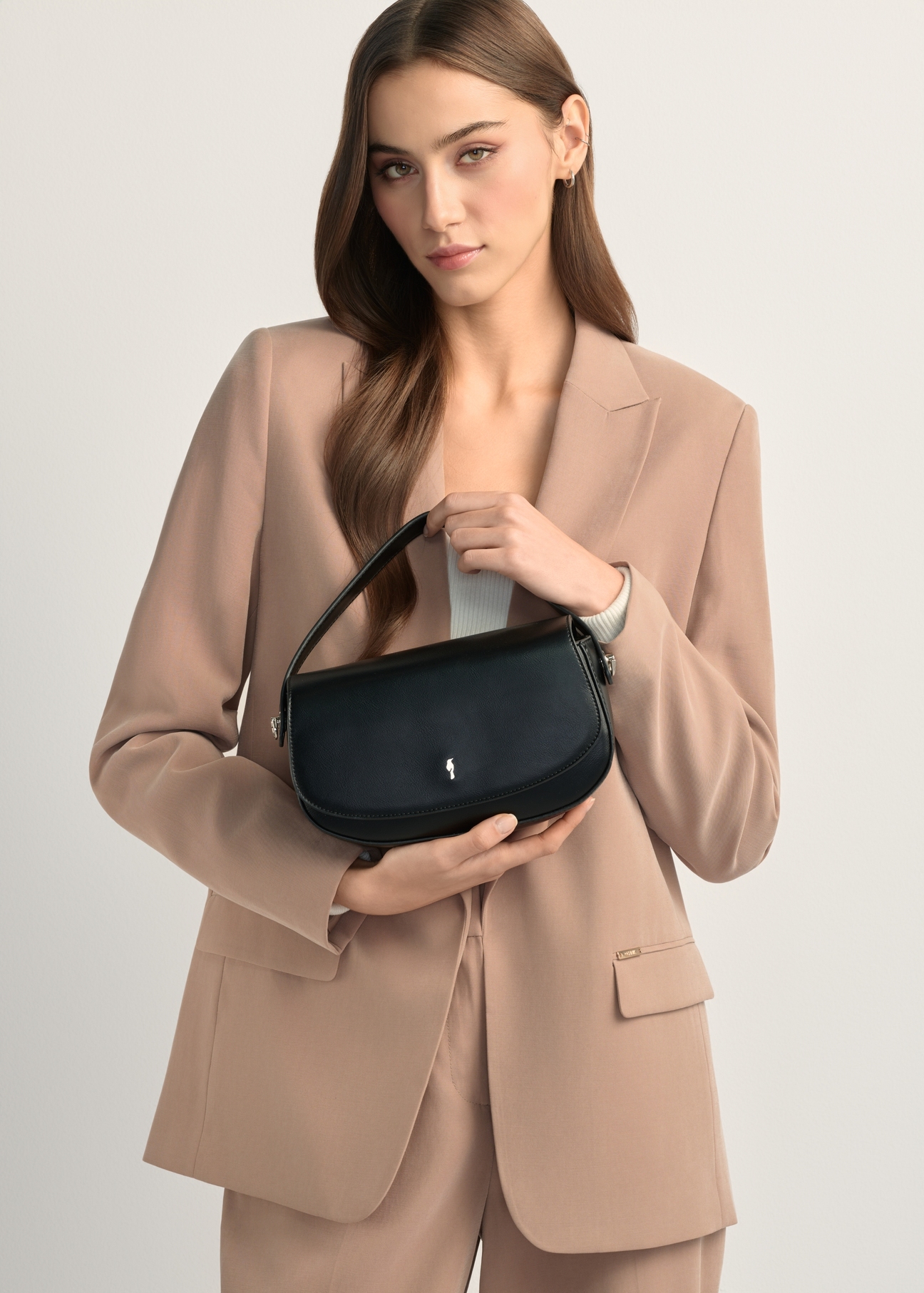 Маленька чорна жіноча сумка-месенджер TOREC-1185-99(W26), вигляд виробу в руках моделі. Видно половину силуету.