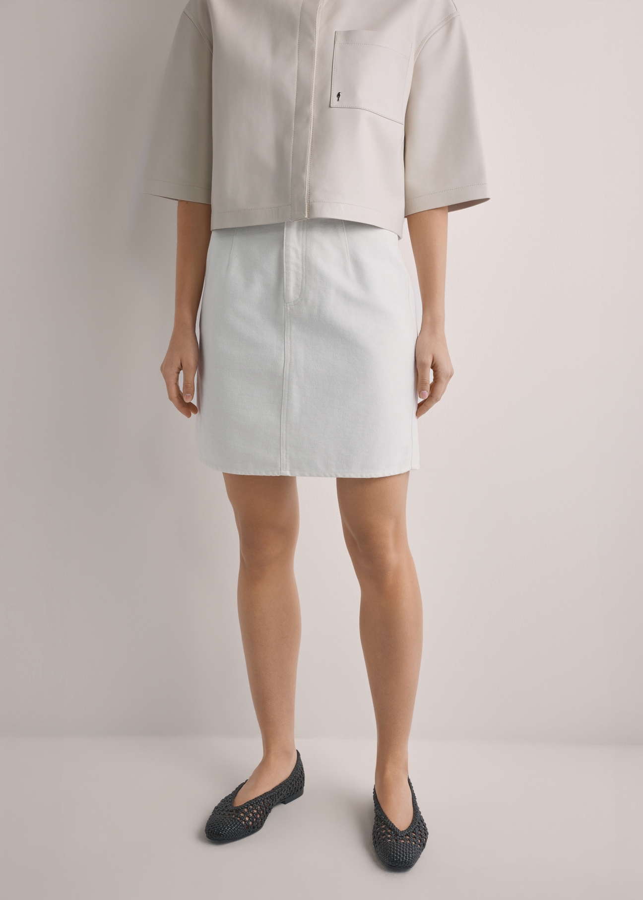 Кремова джинсова міні-спідниця SPCDT-0126-0B(W26), вигляд виробу спереду на моделі. Видно половину силуету.