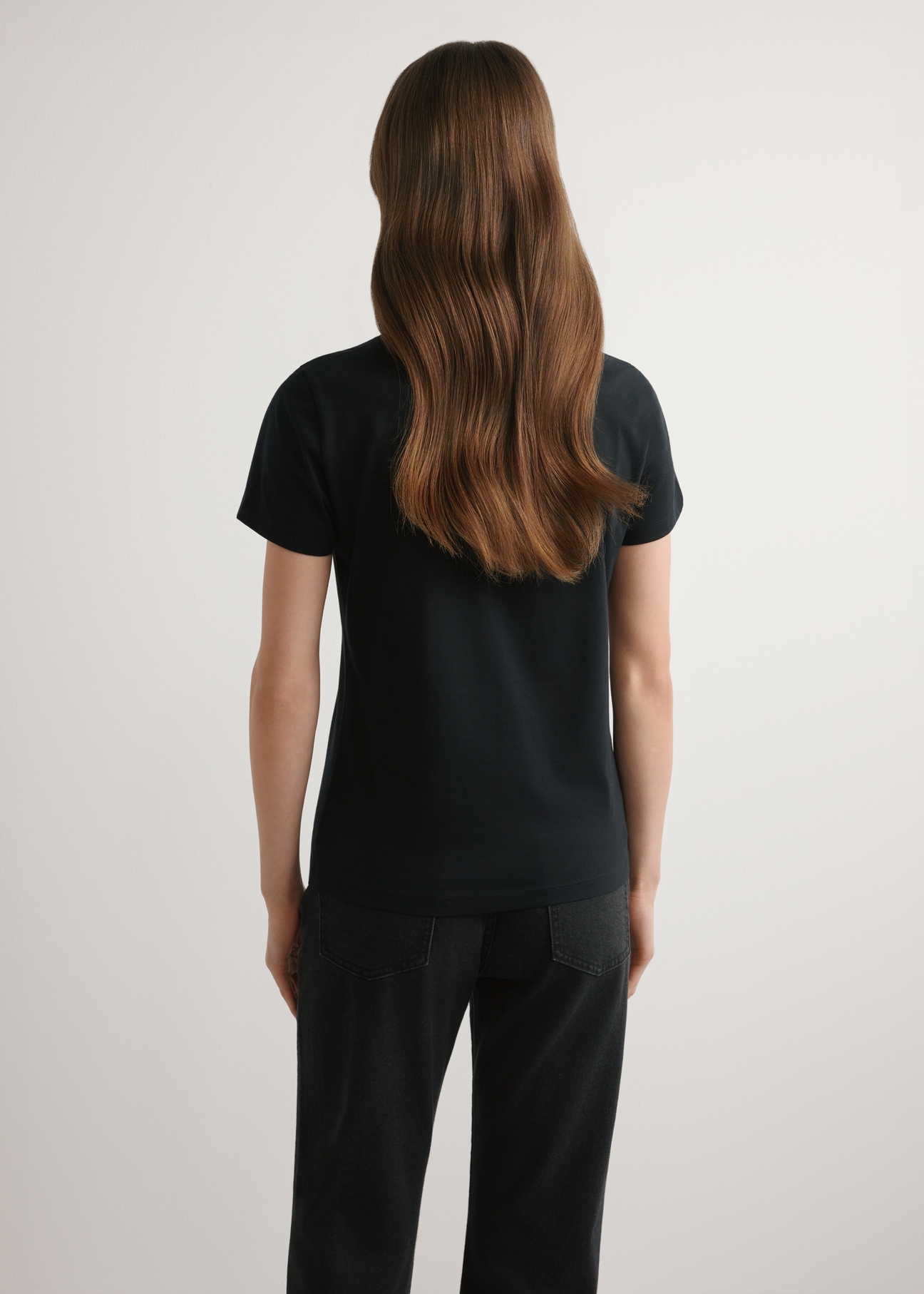 Чорна жіноча футболка з логотипом TSHDT-0155-99(W26), вигляд виробу ззаду на моделі. Видно половину силуету.