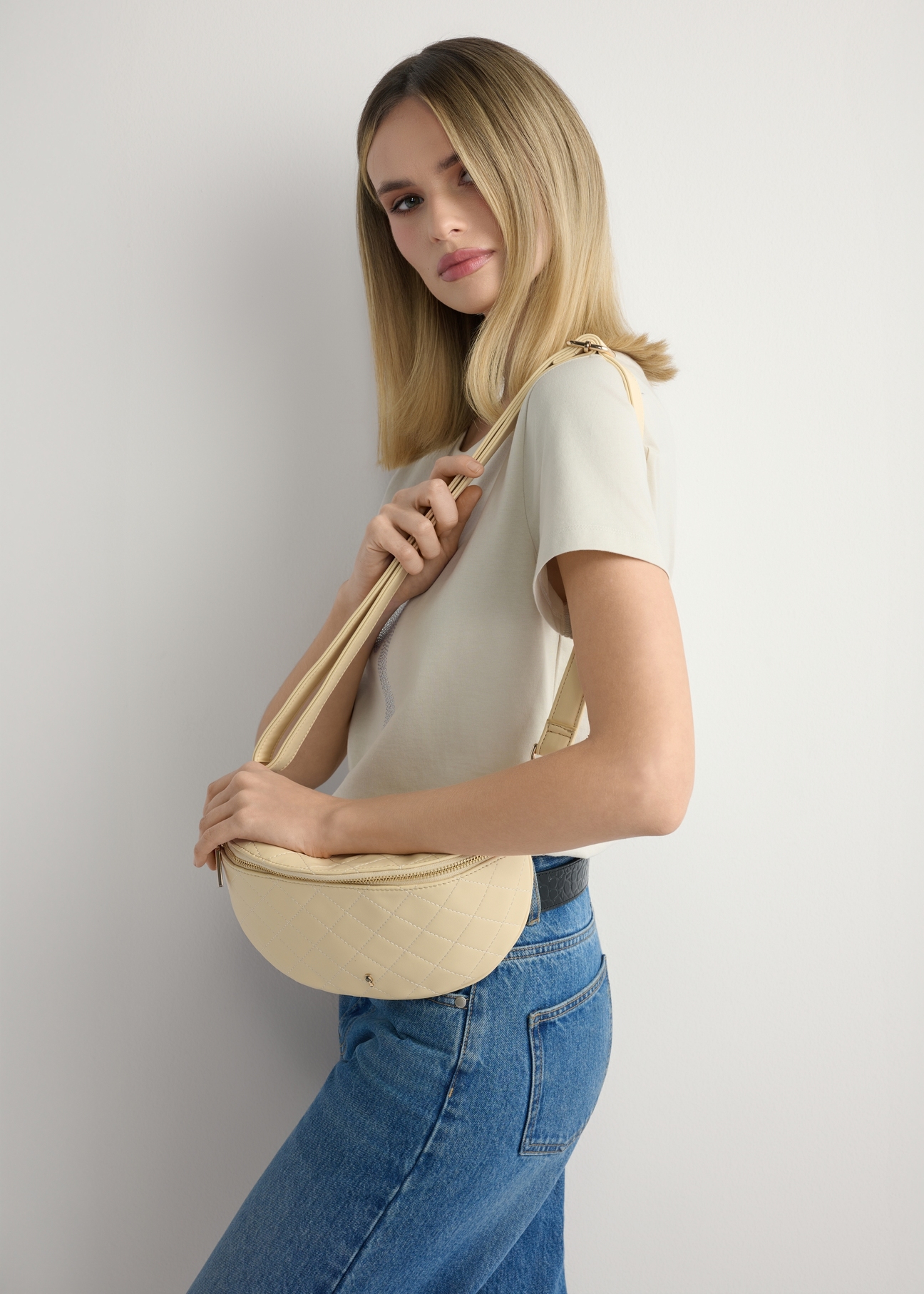 Жіноча стьобана поясна сумка світло-жовтого кольору TOREC-0878-2A(W26), вигляд виробу на плечі моделі. Видно половину силуету.