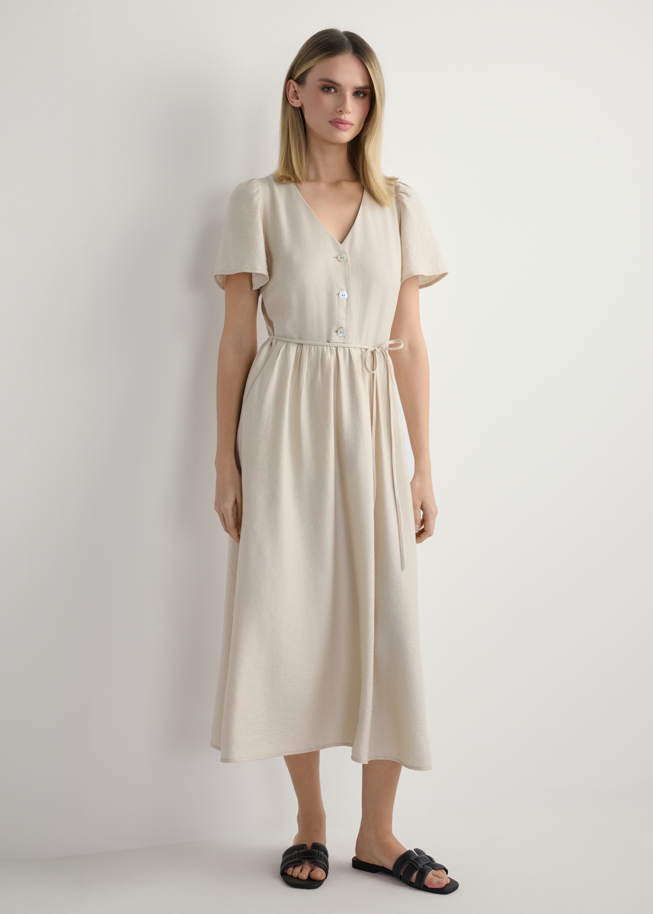 Жіноча світло-бежева сукня SUKDT-0255-1A(W26), вигляд виробу спереду на моделі. Видно все тіло.