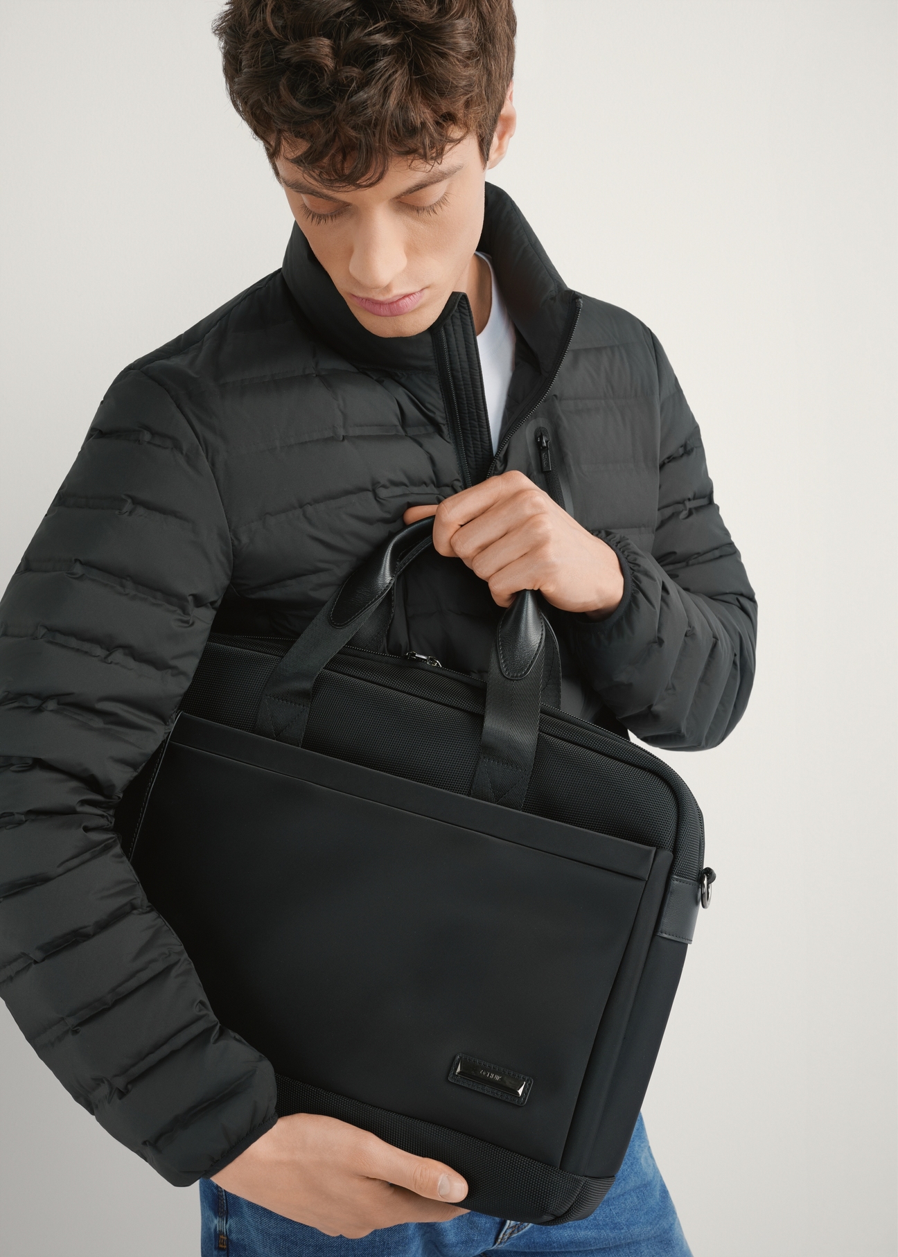 Чорний чоловічий портфель TORMN-0403-99(W26), вигляд виробу спереду в руках моделі. Видно половину силуету.