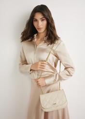 Жіноча сумка кремової лакованої шкіри TORES-1297-0B(W26), вигляд виробу спереду на моделі. Видно силует до коліна.