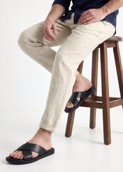 Чоловічі чорні шкіряні шльопанці BUTYM-0536-99(W26), вигляд виробу збоку на ногах моделі, на світлому фоні.