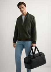 Чорна дорожня сумка TORMN-0412-99(W26), вигляд виробу в руці моделі. Видно повністю.