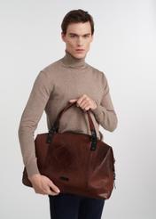 Коричнева шкіряна велика чоловіча сумка TORMS-0103-1H(W26), вигляд виробу в руках моделі, на світлому фоні.